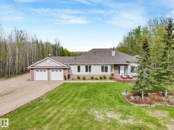 Contemporary ranch-style residence featuring a double attached garage, extensive gravel driveway, and a spacious front lawn - 