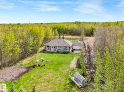Ranch-style residence featuring a covered front porch, an attached garage, a spacious manicured lawn, a tilled garden area, and a greenhouse - 