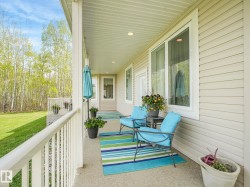 Covered front porch featuring a concrete surface, white railings, and light-colored siding - 