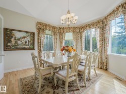 Spacious dining area featuring large bay windows, light wood-finish flooring, and a chandelier light fixture - 