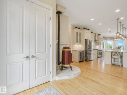 Open-concept kitchen featuring light wood-finish flooring, white cabinetry, stainless steel appliances, and an island with pendant lighting - 