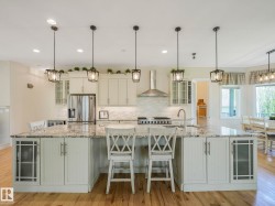 Kitchen featuring a large island with stone countertop, stainless steel appliances, recessed lighting, and pendant lights - 