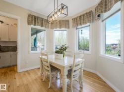 Dining space featuring light wood-finish flooring, a contemporary black metal chandelier, and a bay window configuration with multiple casement windows - 
