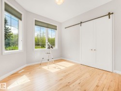 Bright room featuring two large windows with horizontal blinds, natural wood-finish flooring, and white baseboards - 