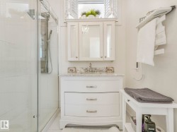 Bathroom featuring a glass-enclosed shower with a multi-function shower panel, a white vanity with a marble-finish countertop, a single basin, a chrome faucet, and a mirrored medicine cabinet - 