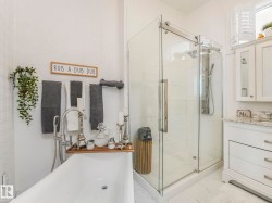 Freestanding soaking tub with a floor-mounted faucet, complemented by a glass-enclosed shower with a multi-function shower panel - 