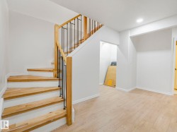 Staircase featuring wood treads, white risers, and a railing with wood handrails and black metal balusters - 