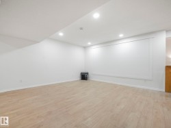 Spacious room with light wood-finish flooring, recessed lighting, and white baseboards - 