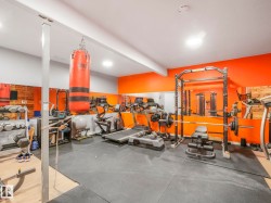 Dedicated fitness area featuring rubber mat flooring, mirrored walls, recessed lighting, and vibrant accent walls - 