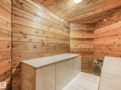 Interior sauna with full wood-paneling, integrated stone heater, and marble-look tiled benches - 
