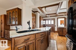 Kitchen featuring an island with a dual basin sink, light-toned countertop, and dark wood-finish cabinetry - 