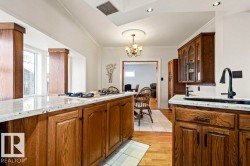 Kitchen featuring wood-finish cabinetry, light-toned countertops, and a built-in cooktop on the island - 