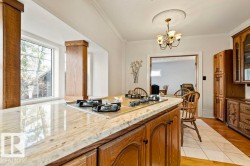 Kitchen island featuring a built-in cooktop, stone countertop, and wood cabinetry - 