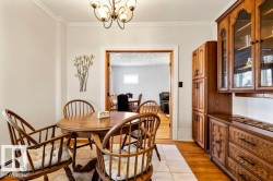 Dining area featuring a classic chandelier, crown molding, a built-in hutch with glass-front cabinetry, a tall pantry cabinet, and wood-finish flooring - 