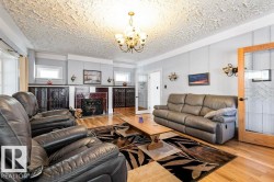 Living area featuring wood-finish flooring, a central fireplace with decorative tile surround, built-in cabinetry with patterned glass inserts, and a textured ceiling - 