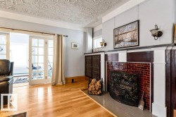 Living area featuring wood-finish flooring, a brick fireplace with a decorative screen, and sconce lighting - 