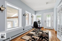 Light-filled interior space featuring multiple windows with white trim, wood-finish flooring, and a white paneled door with glass inserts - 
