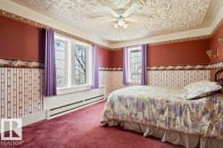 Room featuring multiple windows, textured ceiling, ceiling fan with light fixture, wall sconces, and baseboard heating - 