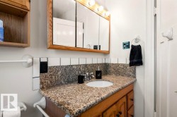 Bathroom vanity featuring a granite countertop, undermount sink, and wood-finish cabinetry - 