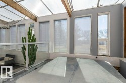 Enclosed sunroom with a hot tub featuring a clear protective cover, multiple windows, and a transparent ceiling - 