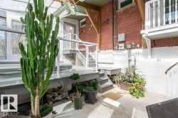 Lower-level patio featuring concrete flooring, a painted brick foundation, and wooden structural beams - 