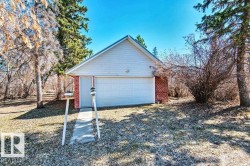 Detached garage featuring white siding and brick construction - 