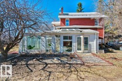 Brick exterior with a metal roof and a sunroom addition featuring a full glass wall and double French doors - 