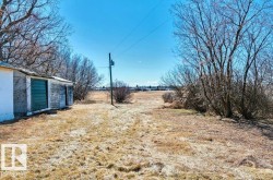 Expansive open lot with a utility shed featuring green double doors and a weathered exterior - 