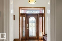 Arched wood entry door with ornate leaded glass, flanked by coordinating sidelights and a transom window - 