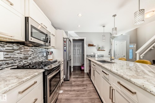 Kitchen featuring a gas range, stainless steel appliances, light-toned cabinetry, light-toned countertops, and a patterned tile backsplash - 267 Sturtz Bend, Leduc, AB - Indoor Photo Showing Kitchen With Double Sink With Upgraded Kitchen