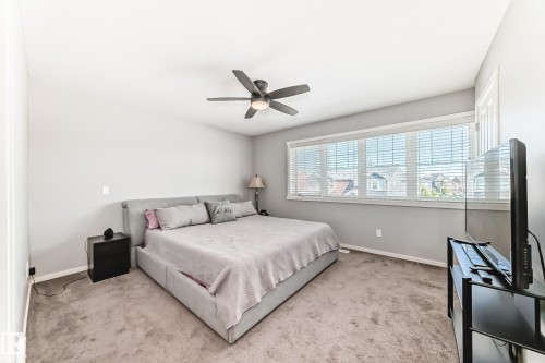 Spacious room featuring carpeting, multiple windows with blinds, and a built-in ceiling fan with integrated lighting - 267 Sturtz Bend, Leduc, AB - Indoor Photo Showing Bedroom