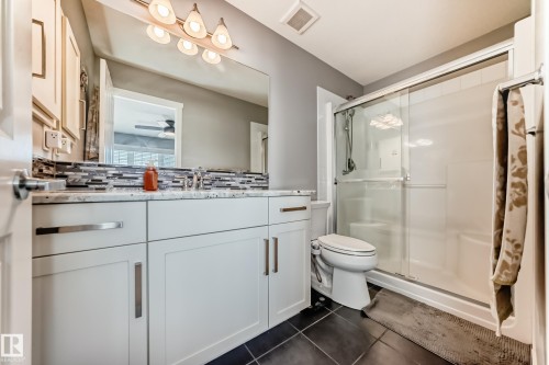 Bathroom with white shaker-style cabinetry, a vanity with a light-toned countertop, and a mosaic tile backsplash - 267 Sturtz Bend, Leduc, AB - Indoor Photo Showing Bathroom