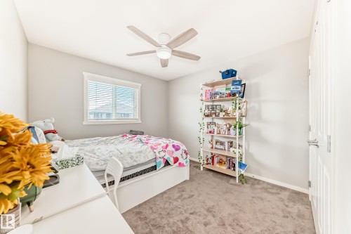 Bedroom featuring neutral-toned carpeting, a window with horizontal blinds, and a built-in ceiling fan with light fixture - 267 Sturtz Bend, Leduc, AB - Indoor Photo Showing Bedroom