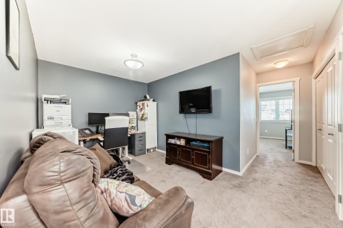 Carpeted room with a dedicated workspace, featuring a built-in office desk, overhead lighting, and a wall-mounted media cabinet - 267 Sturtz Bend, Leduc, AB - Indoor