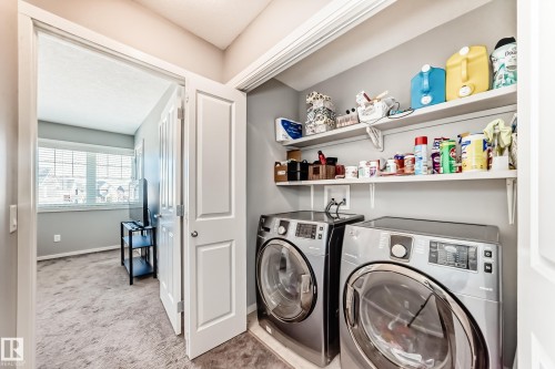 Dedicated laundry area featuring front-loading appliances and two wall-mounted storage shelves - 267 Sturtz Bend, Leduc, AB - Indoor Photo Showing Laundry Room