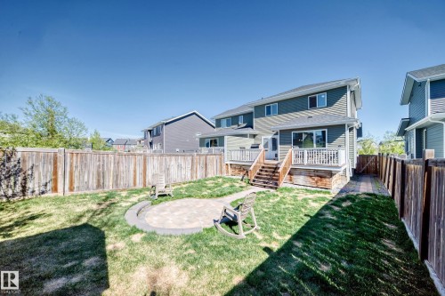 Spacious backyard featuring a paver patio with a stone border, green lawn, and full privacy fencing - 267 Sturtz Bend, Leduc, AB - Outdoor With Deck Patio Veranda