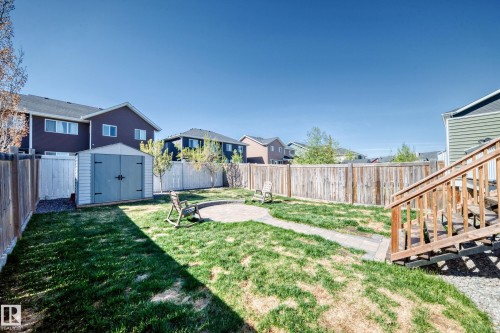 Fenced backyard featuring a circular stone patio, a stone pathway, a storage shed, and a wooden staircase - 267 Sturtz Bend, Leduc, AB - Outdoor