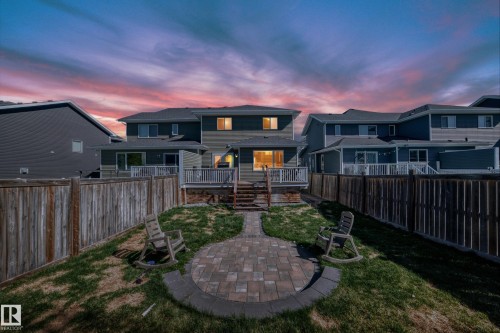 Backyard featuring a paver patio with a curved border, wooden privacy fencing, and a multi-level deck with white railings - 267 Sturtz Bend, Leduc, AB - Outdoor With Deck Patio Veranda