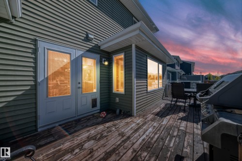 Raised wooden deck with a double glass-paned door entry, multiple windows featuring interior blinds, and dark horizontal siding - 267 Sturtz Bend, Leduc, AB - Outdoor With Deck Patio Veranda With Exterior