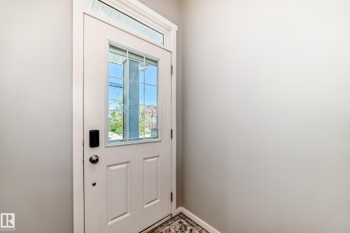 Entry door with a grid-patterned glass insert, a transom window, and a smart lock - 267 Sturtz Bend, Leduc, AB - Indoor Photo Showing Other Room