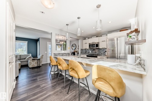 Modern kitchen featuring an extended white countertop, stainless steel appliances, a tiled backsplash, and recessed lighting - 267 Sturtz Bend, Leduc, AB - Indoor