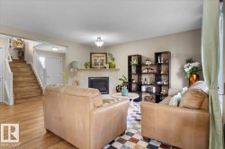 Living area featuring a fireplace with a light-toned mantel, wood-finish flooring, and a white paneled entry door - 