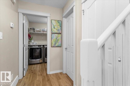 Dedicated laundry area featuring a washer and dryer, wire shelving, and wood-finish flooring - 3356 25 Ave, Edmonton, AB - Indoor
