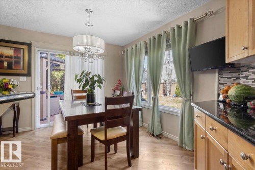 Dining area with wood-finish flooring and a multi-light chandelier - 3356 25 Ave, Edmonton, AB - Indoor Photo Showing Dining Room