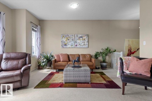 Carpeted living area featuring light neutral wall tones, a white ceiling, and a prominent window with white trim - 3356 25 Ave, Edmonton, AB - Indoor Photo Showing Living Room