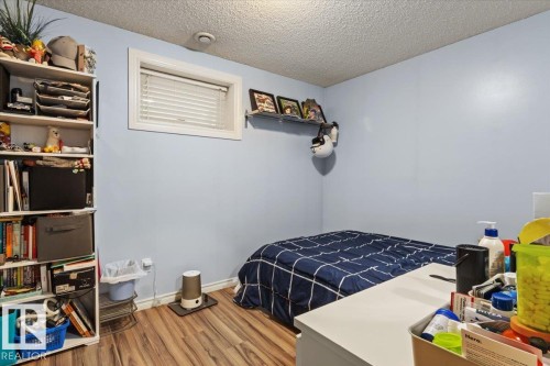 Room featuring wood-finish flooring, a single window with blinds, and light blue painted walls - 3356 25 Ave, Edmonton, AB - Indoor Photo Showing Bedroom
