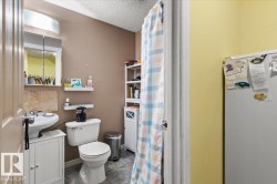 Pedestal sink with white vanity base, toilet, and tiled flooring - 