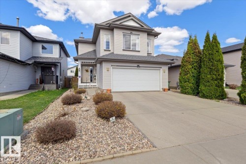 Two-story residential property featuring a double-car garage, concrete driveway, and a rock-landscaped front yard with established shrubs - 3356 25 Ave, Edmonton, AB - Outdoor With Facade