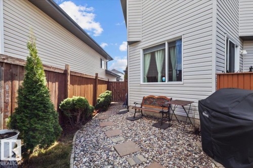 Side yard featuring a stone pathway with square paver accents and established evergreen landscaping - 3356 25 Ave, Edmonton, AB - Outdoor With Exterior