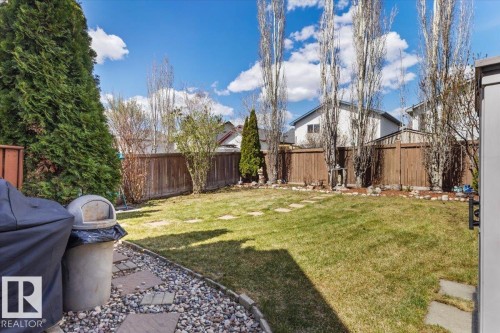 Expansive backyard featuring a lush lawn, stepping stone pathway, decorative gravel border, and tall privacy fencing - 3356 25 Ave, Edmonton, AB - Outdoor